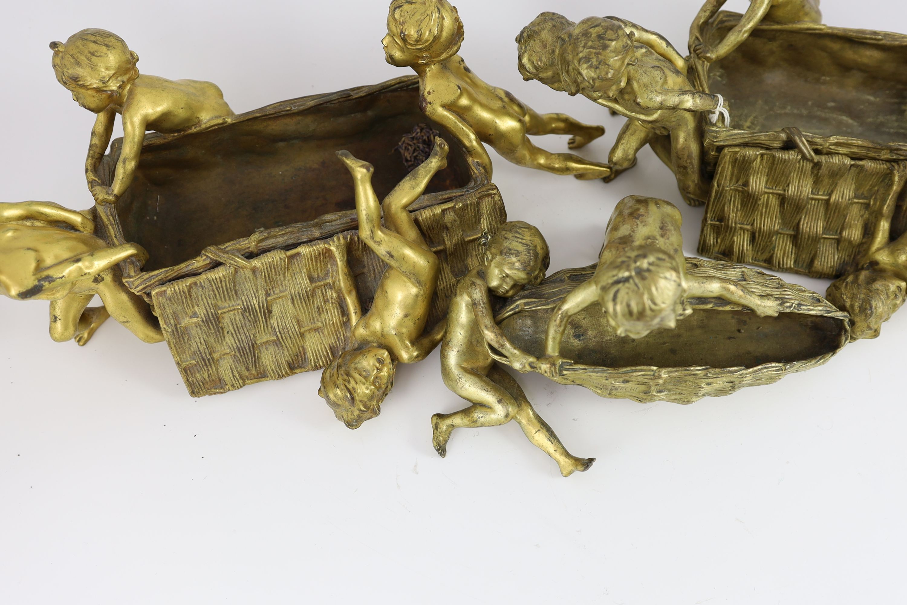 Raoul Francois Larche (French, 1860 - 1912). A set of three ormolu groups of children pushing and pulling large wicker baskets, largest length 45cm height 17cn smaller length 27cm height 16cm